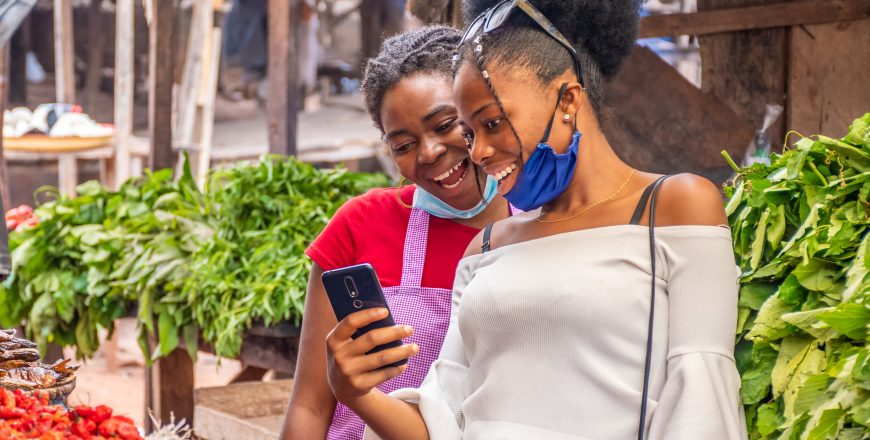 duas-mulheres-visualizando-conteudo-em-um-telefone-em-um-mercado-local-africano